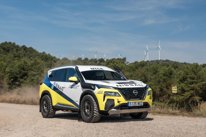 Der Nissan X‑Trail Rennwagen für die Baja Aragon Rallye 2024 steht auf einem Schotterplatz vor einem bewaldeten Hügel