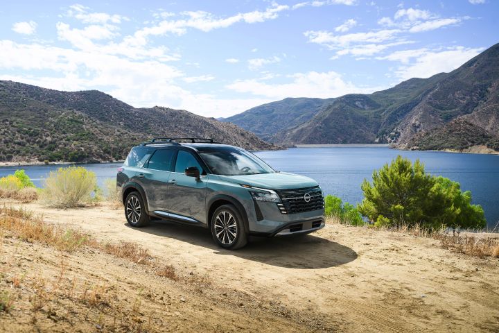 Front right 3/4 view of the 2026 Nissan Pathfinder parked on a dirt path overlooking a body of water.