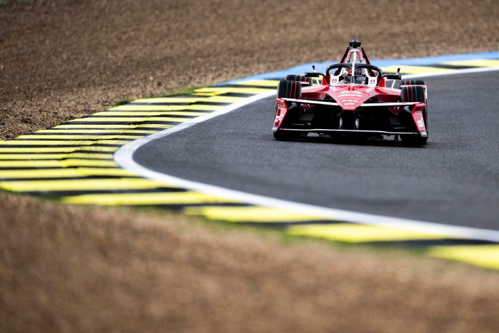 Frontalaufnahme von Norman Nato im Nissan Formel E Rennwagen e‑4ORCE 05 mit der Startnummer 23 auf der Rennstrecke in Madrid, auf der gelbe und schwarze Randsteine sowie Kies zu sehen sind; das Auto befindet sich in der oberen rechten Ecke des Bildes.