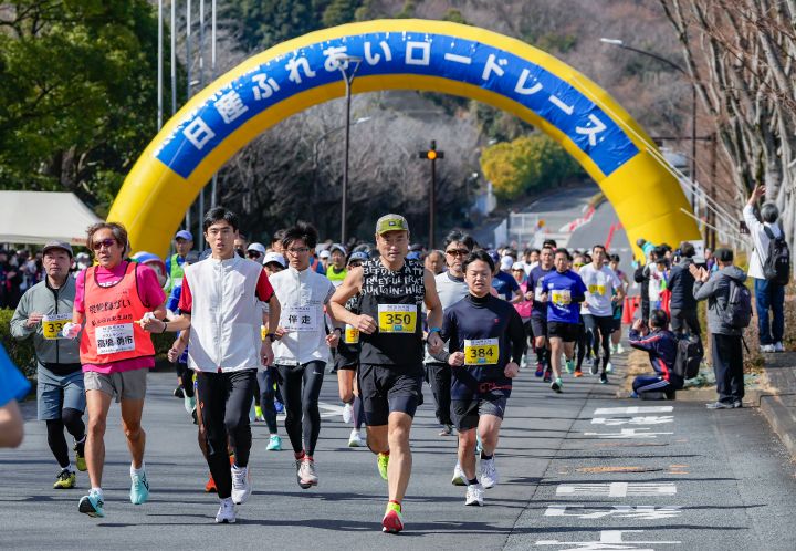 第14回 日産ふれあいロードレースを走る多くの参加者がゴールのアーチを駆け抜けていく様子。