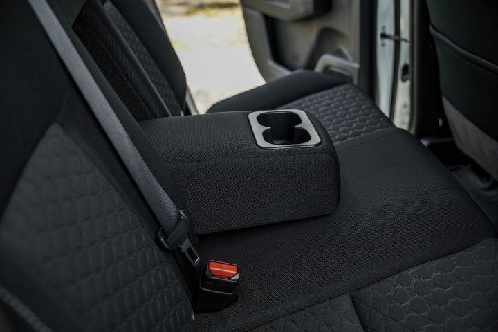 2026 Nissan Navara SL dual cab ute finished in Alpine White with a rear-seat close-up showing the folded centre armrest and built-in cupholder.