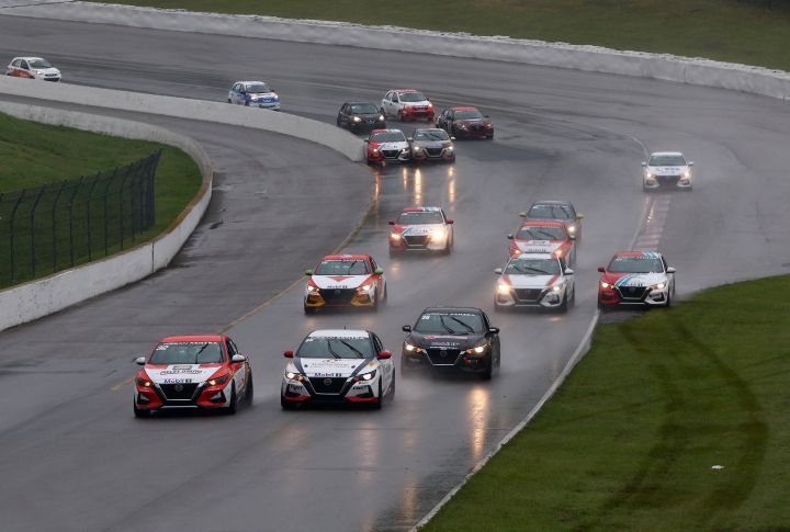 Group of Nissan Sentra Cup cars driving on a wet track.