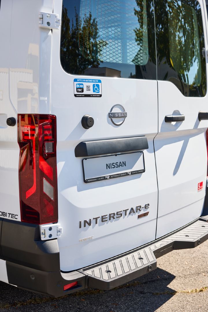 Detailaufnahme vom Heck des Nissan Interstar-e mit MobiTEC Ausbau mit Typenschriftzug und einem Aufkleber, der auf den Rollstuhllift hinweist
