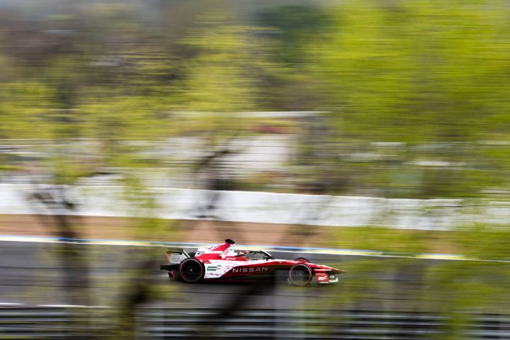 Seitenaufnahme von Norman Nato im Nissan e‑4ORCE 05 Formel E Rennwagen mit der Startnummer 23 auf der Rennstrecke in Madrid, sichtbar durch die Bäume.