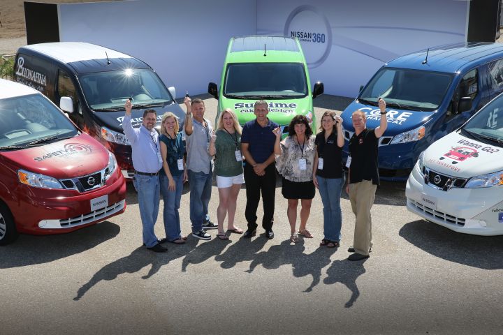 several people with a key pictured with Nissan vehicles around them