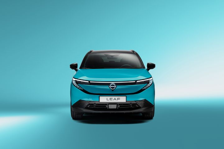 Vue frontale directe de la nouvelle Nissan LEAF bleu turquoise avec les phares allumés sur un fond de studio également bleu turquoise