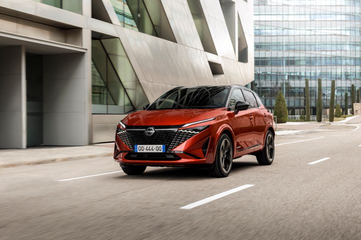 Ein roter Nissan Qashqai fährt auf einer Straße im städtischen Umfeld