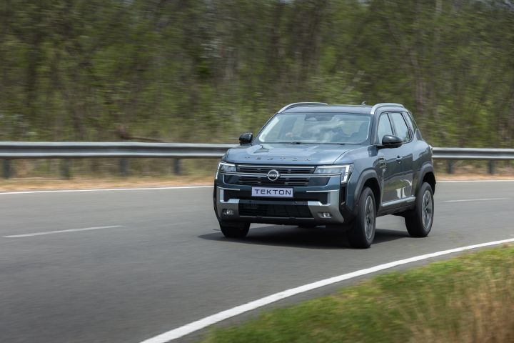 Nissan Tekton driving through a bend, highlighting its SUV stance and proportions.