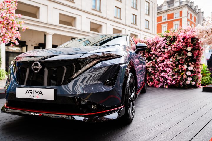 ¾ angle of the Ariya Nismo showing the front face with both the buildings of Covent Garden and artificial cherry blossom in the background.