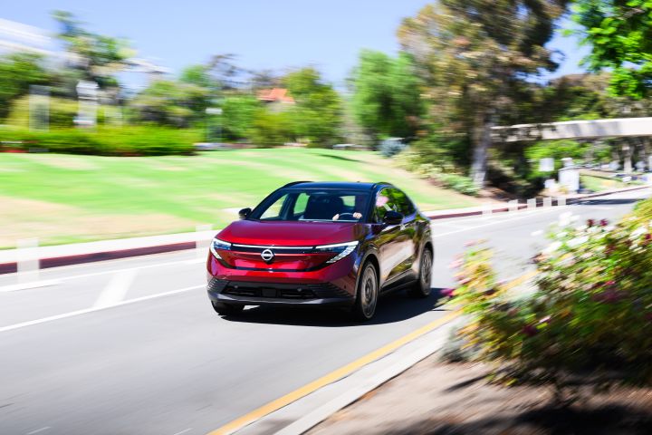 2026 Nissan LEAF driving along a road line with grass and landscaping.