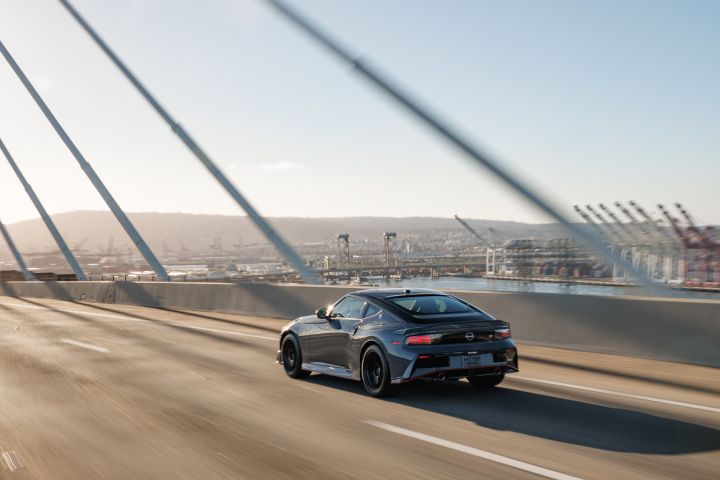 Rear angled view of the 2027 Nissan Z NISMO MT driving on a highway bridge.