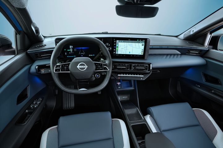 full dashboard view of cockpit from driver POV showing steering wheel. driver focused infotainment, front seats, and blue ambient lights below the dashboard. Google maps navigation on screen
