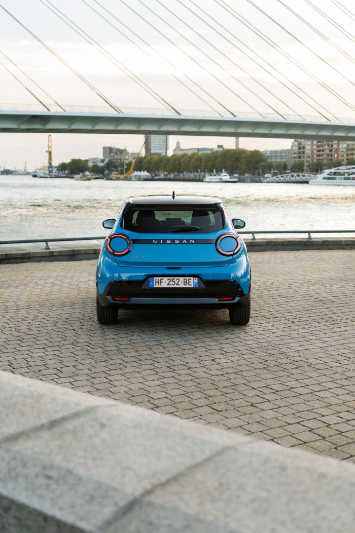 Frontale Heckansicht eines Nissan Micra mit Wasser und Gebäuden von Rotterdam im Hintergrund