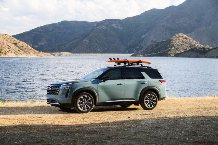 Left profile view of the 2026 Nissan Pathfinder parked in front of a body of water with a surfboard strapped to the roof.