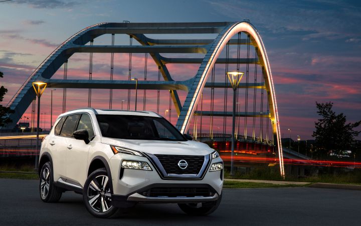 A white 2021 Nissan Rogue parked near an illuminated bridge