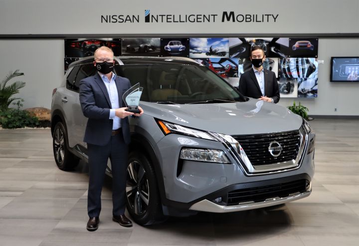 Two men in suits standing next to a Nissan Intelligent Mobility SUV.