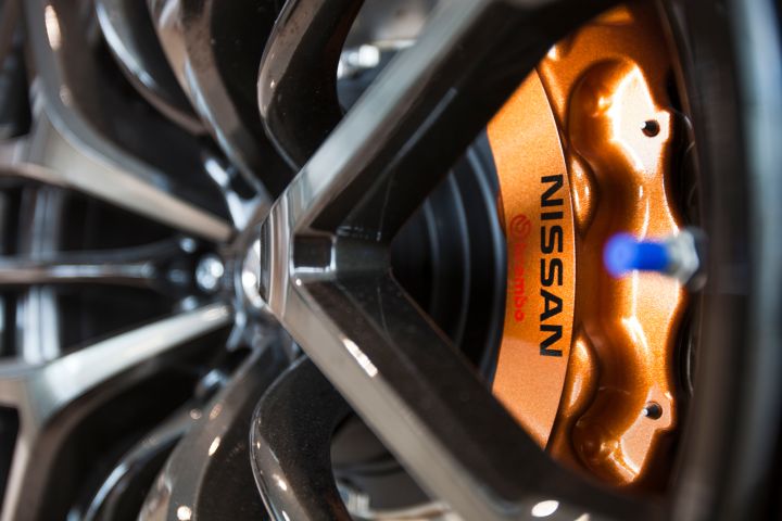 Gros plan sur la jante en alliage noir d'une voiture Nissan avec un étrier de frein orange visible.