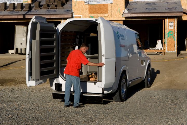 a man in a red shirt opening the back of a Nissan NV2500 Concept