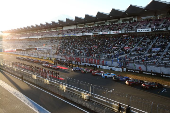 Auf der Start- und Zielgeraden des Fuji Speedway stehen viele Nissan Sportwagen und ihre Fahrer