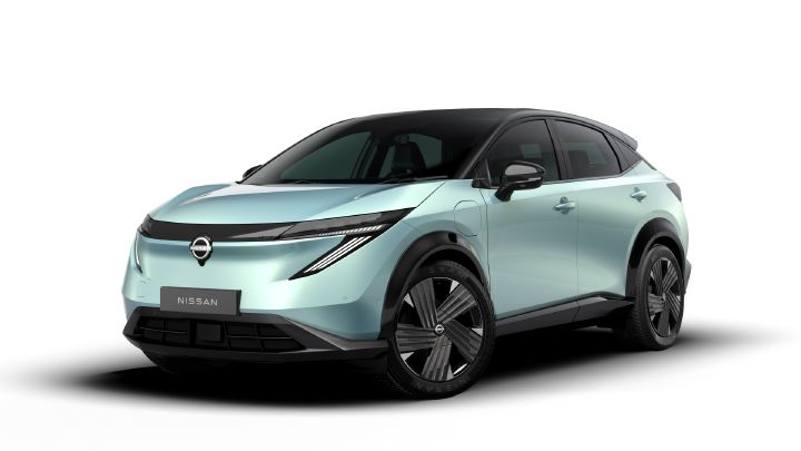A light blue vehicle is photographed from the front, featuring smooth body lines and sharp headlights. The background is an outdoor exhibition space.