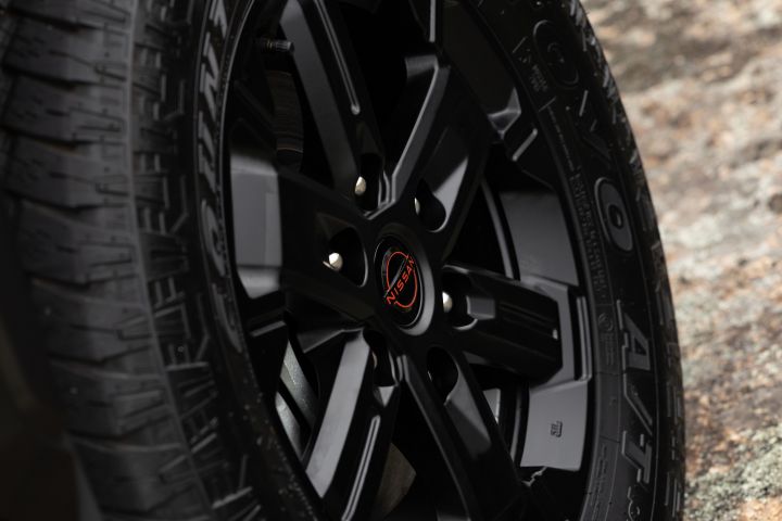 2026 Nissan Navara PRO-4X finished in Boulder Grey highlighting the black alloy spokes, Nissan centre cap and all-terrain tyre sidewall texture.