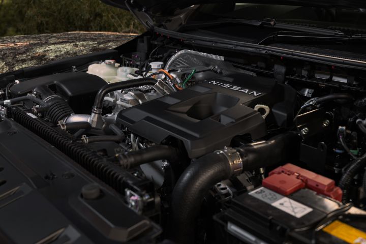 2026 Nissan Navara PRO-4X finished in Boulder Grey showing the engine bay with Nissan engine cover, intake piping, coolant reservoir, battery and under-bonnet components.