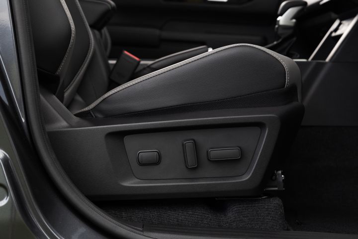 Close-up of the side of a front seat in a 2026 Nissan Navara ST-X, showing the power seat adjustment controls, seat base, and lower seat trim.