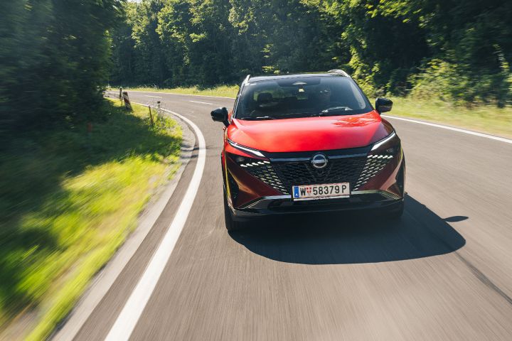Ein Nissan Qashqai in Fuji Sunset Red fährt durch eine Landstraßenkurve