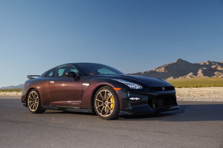 Front right 3/4 view of the Midnight Purple 2024 GT‑R T-spec Takumi parked on a road with blue skies behind.
