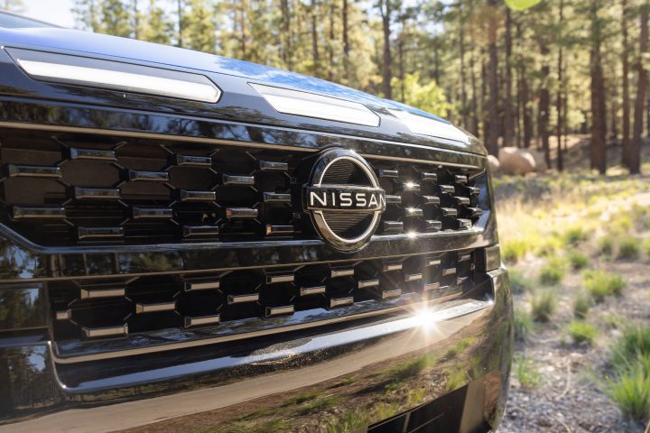 Close up of the grill on the 2027 Nissan Frontier Sport Edition with trees behind.