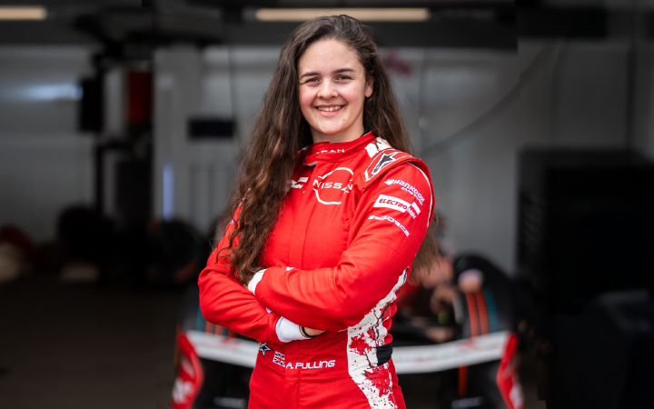 Nissan Formula E Team's rookie and simulator driver Abbi Pulling in the red Nissan Formula E Team race suit smiling with her arms crossed in front of the team garage in Berlin.