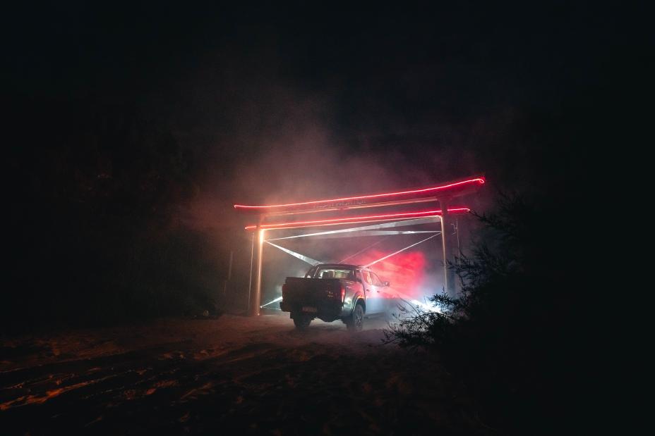 Una Nissan Frontier atravesando un arco Torii en la playa.