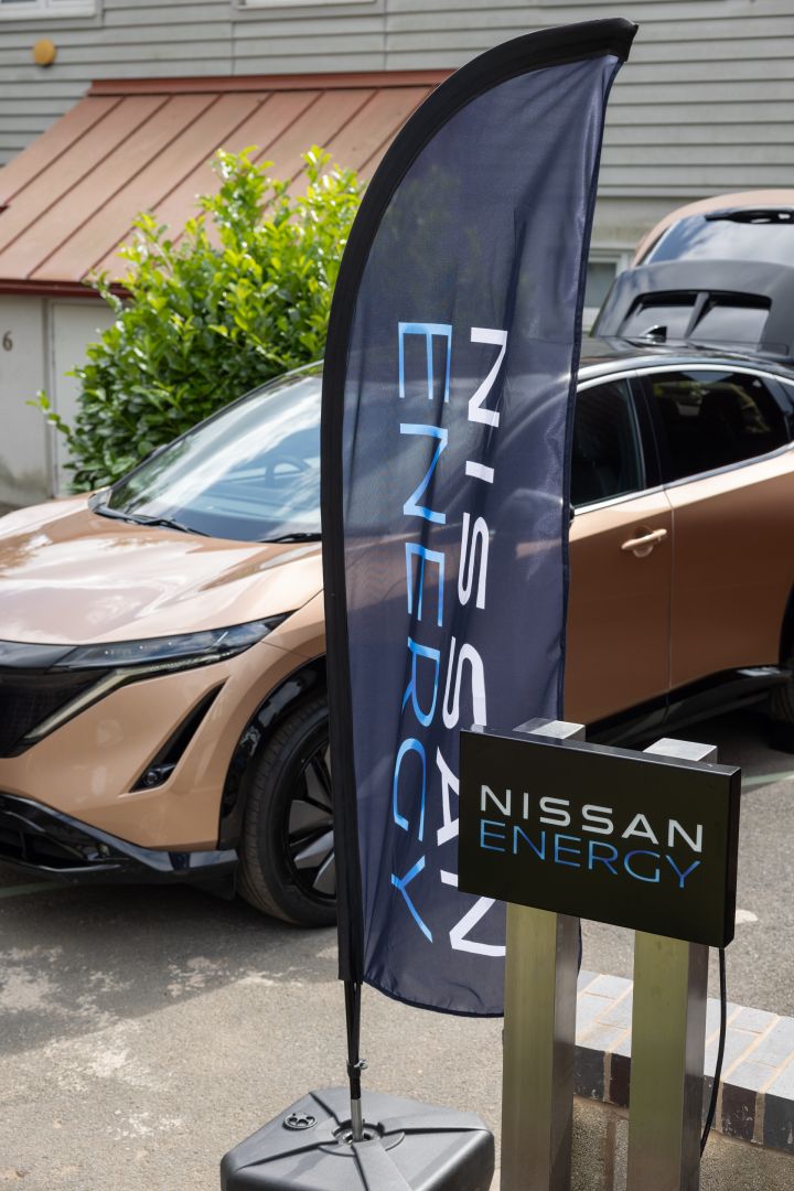Nissan Ariya garé derrière un drapeau avec le logo Nissan Energy.