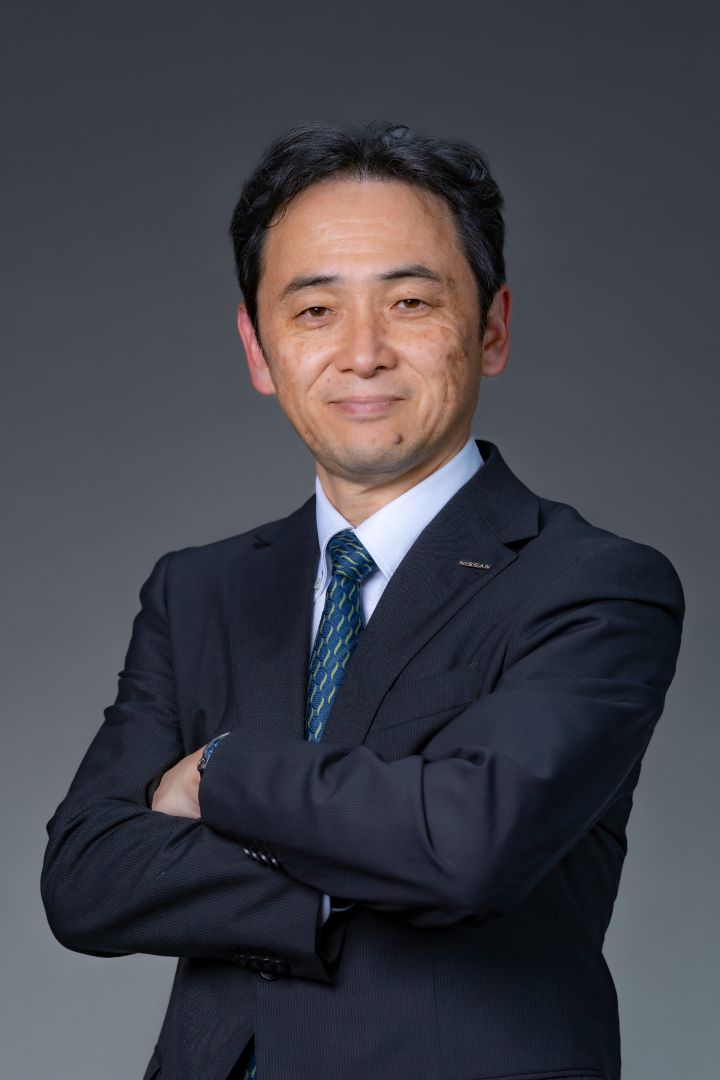 Portrait of Eiichi Akashi with his arms folded (suit, tie and NISSAN corporate pin)