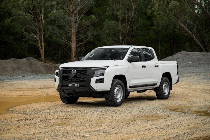 2026 Nissan Navara SL dual cab ute finished in Alpine White captured at a front-left three-quarter angle, showing the tray, black cladding and off-road-ready ground clearance.