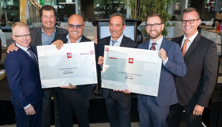 Six hommes en tenue professionnelle souriant et tenant des récompenses lors d'un événement Nissan.