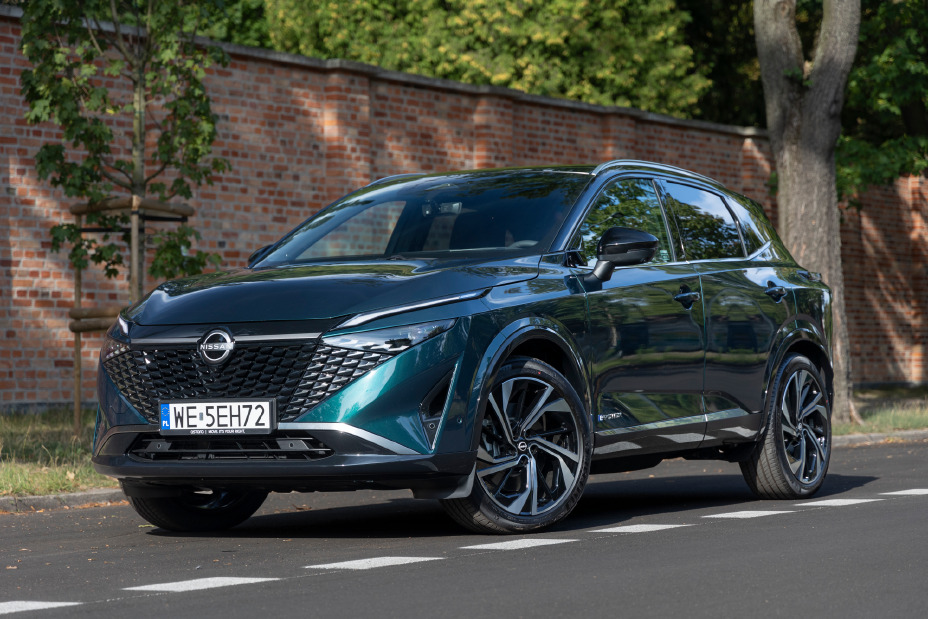 Zielony Nissan Qashqai stojący z murem ceglanym w tle