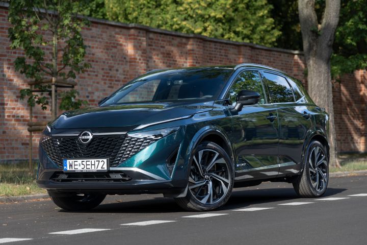 Zielony Nissan Qashqai stojący z murem ceglanym w tle