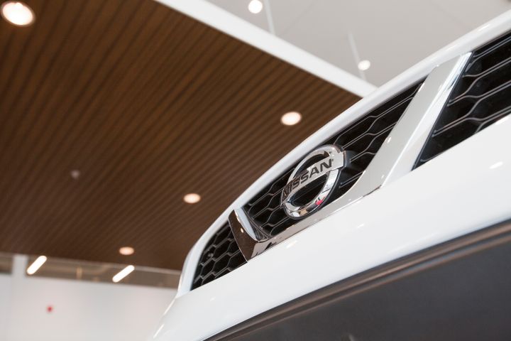 Gros plan sur la calandre blanche d'une voiture Nissan, ornée du logo Nissan.