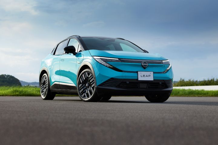 The front view of a turquoise blue Nissan Leaf is captured, highlighting the design of the front grille and headlights.