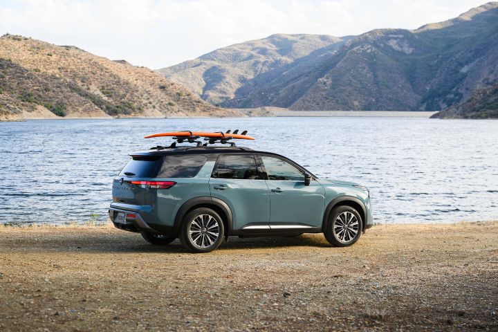Right profile view of the 2026 Nissan Pathfinder with a surfboard strapped to the roof.