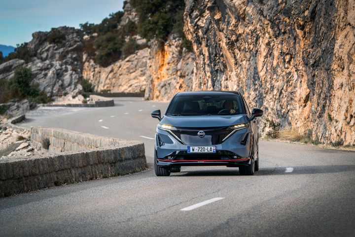 Photo de l’Ariya Nismo vu de devant roulant sur des routes de montagne.