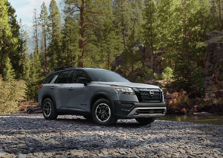Front right ¾ view of a gray Nissan Pathfinder with a nature scene behind.