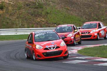 Three red Nissan Micras racing during the Micra Cup