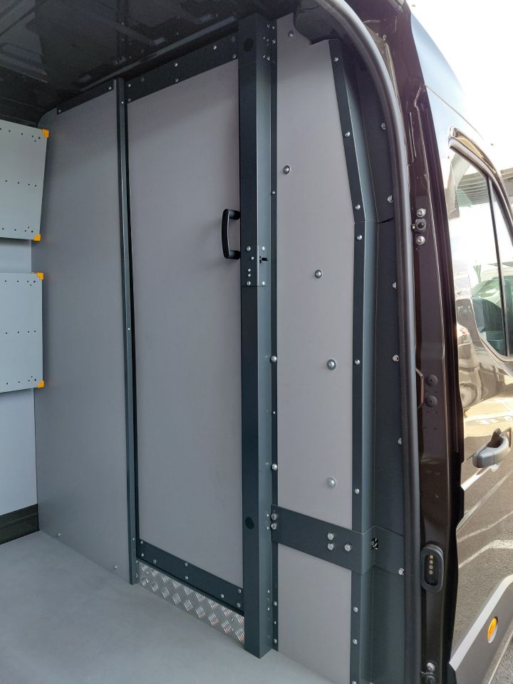Detailaufnahme der Tür zwischen Fahrerkabine und Ladeabteil  im Inneren des Nissan Interstar-e mit KEP-Umbau, aufgenommen durch die geöffnete seitliche Schiebetür