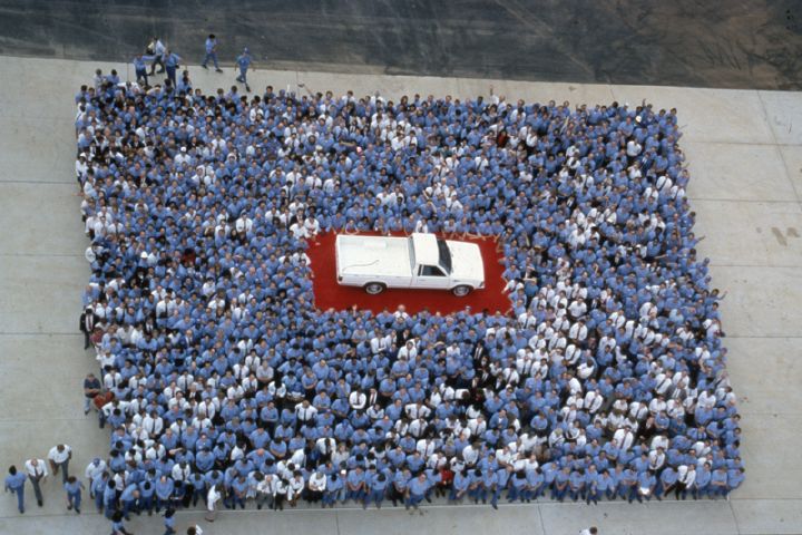 a large group of people surrounding a white 720 pickup in Smyrna