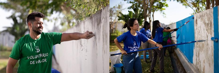 Dois voluntários, um de blusa verde e o outro de blusa azul, preparando o muro de uma escola para receber a pintura
