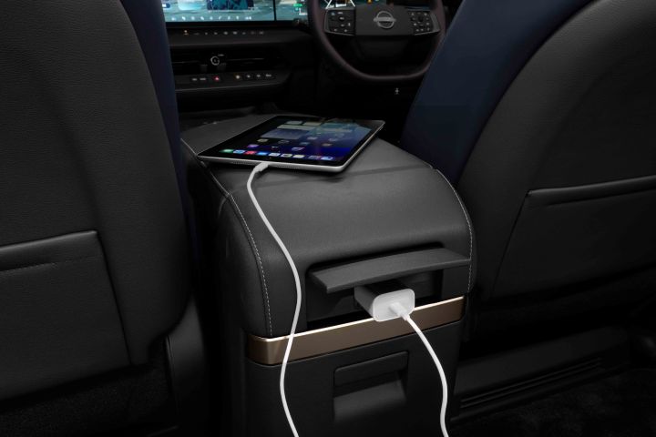 The rear seat area of a Fuji-dawn-colored Elgrand. A charging port is located on the rear center console, with a tablet or smartphone being charged.