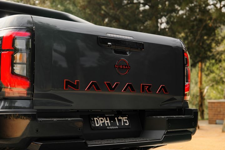 2026 Nissan Navara PRO-4X finished in Boulder Grey pictured from the rear with red-outlined NAVARA tailgate lettering, Nissan badge and vertical tail-lamps.
