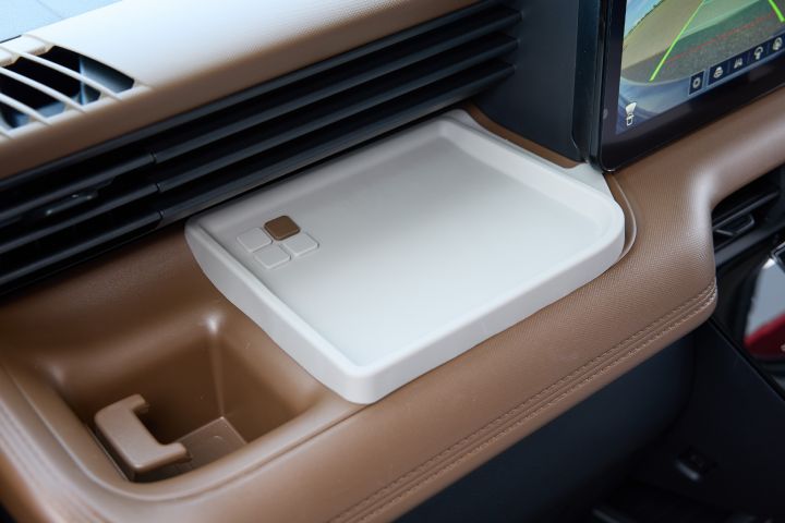 A white inst tray mounted on the dashboard of the new Nissan Roox kei car. Surrounding elements include a brown interior and black air vents, combining functionality with stylish design.